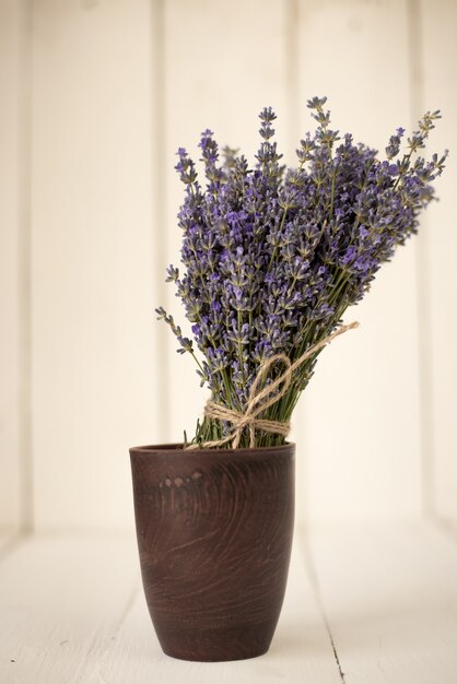 Fresh cut aromatic bouquet of lavender field in a wooden glass on white wood.