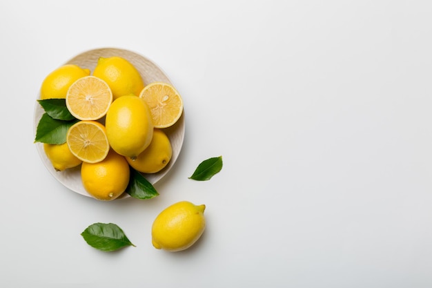 Fresh cutted lemon and whole lemons over round plate on colored background Food and drink ingredients preparing healthy eating theme top view vith copy space