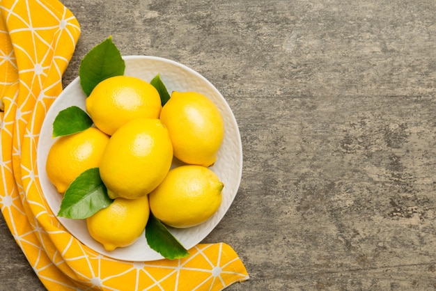 Fresh cutted lemon and whole lemons over round plate on colored background Food and drink ingredients preparing healthy eating theme top view vith copy space