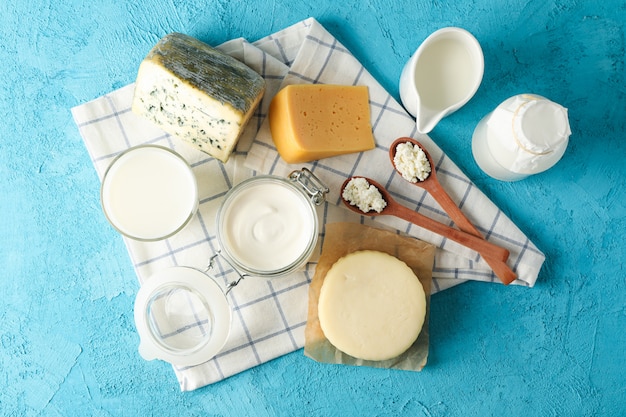 Fresh dairy products and kitchen towel on blue background