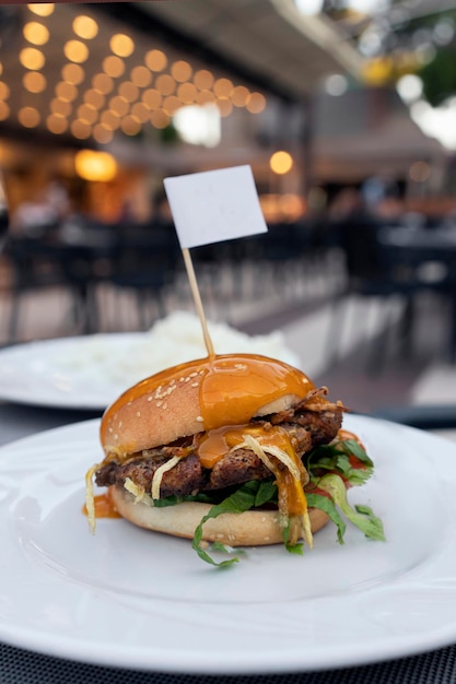 Fresh delicious mouthwatering hamburger with cutlet salad and fried onions and mustard on a plate in