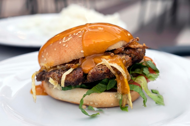 Fresh delicious mouthwatering hamburger with cutlet salad and fried onions and mustard on a plate in