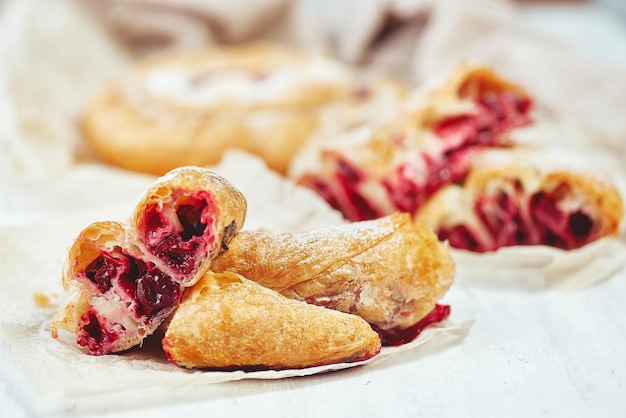 Fresh delicious puff pastry with sweet cherries served on light table