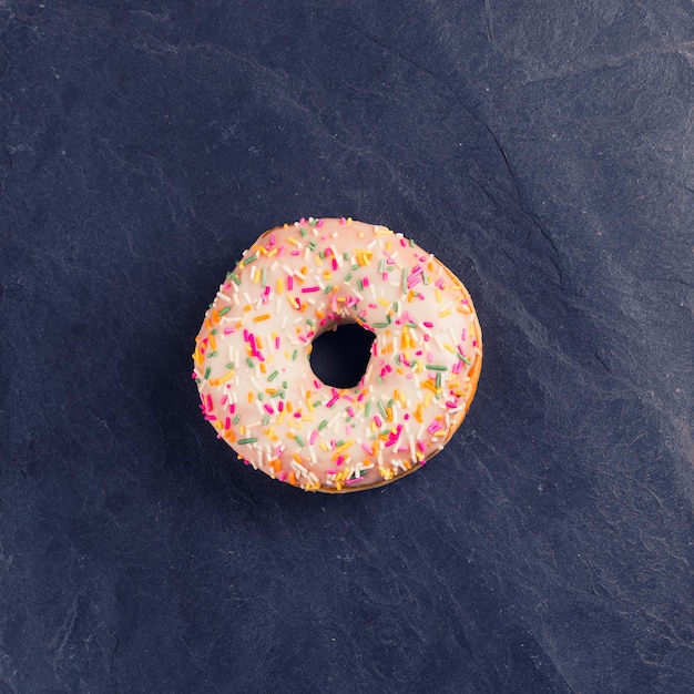 Fresh donut with toppings on a dark background.