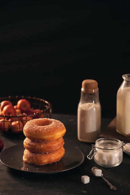 Fresh donuts with sugar powder and coffee with milk on a wooden table. Breakfast in the village.