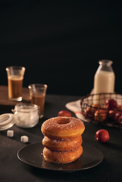 Fresh donuts with sugar powder and coffee with milk on a wooden table. Breakfast in the village.