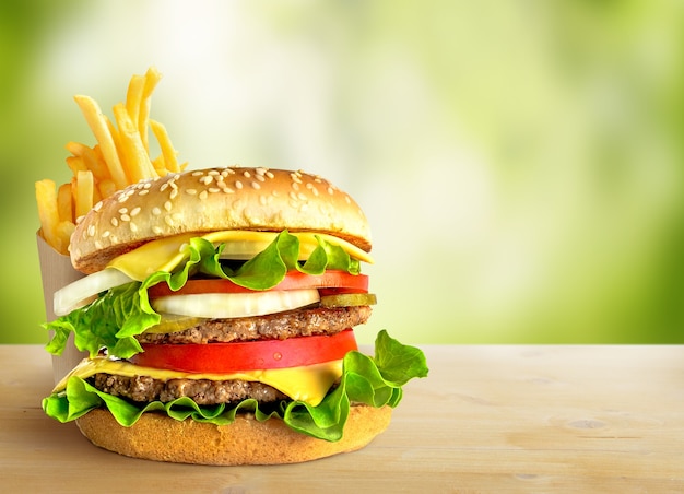 Fresh double hamburger and french fries on green nature background