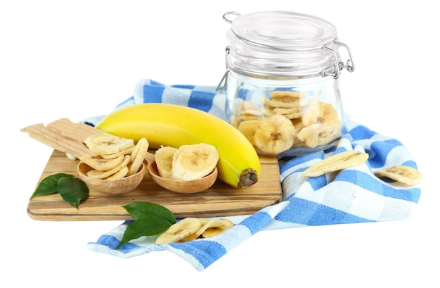 Fresh and dried banana slices in glass jar on cutting board isolated on white