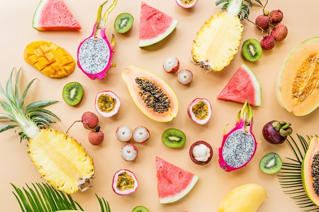 Fresh exotic fruits and tropical palm leaves on pastel orange background