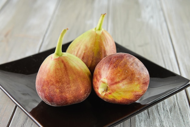 Fresh figs in black plate on wooden background