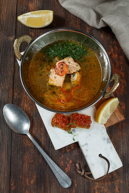 Fresh fish soup with ingredients and spices for cooking. Wooden background