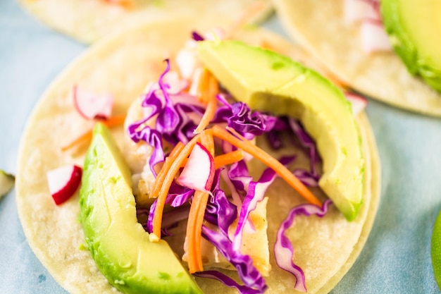 Fresh fish tacos with cod and purple cabbage on a white corn tortillas.