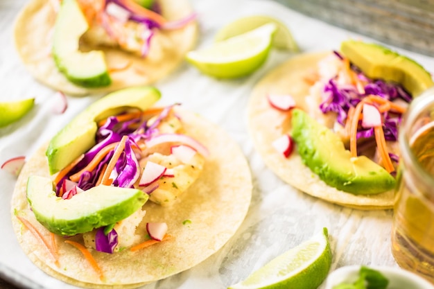 Fresh fish tacos with cod and purple cabbage on a white corn tortillas.