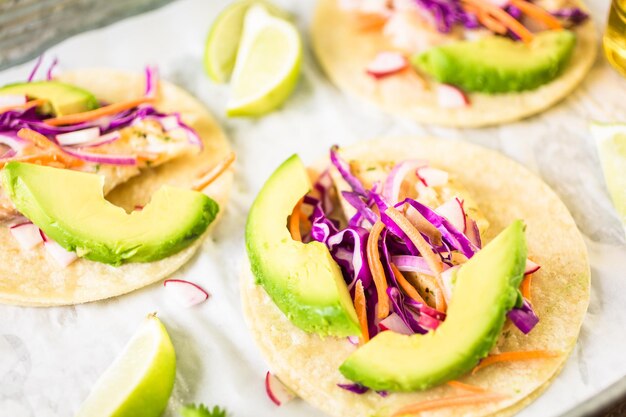 Photo fresh fish tacos with cod and purple cabbage on a white corn tortillas.