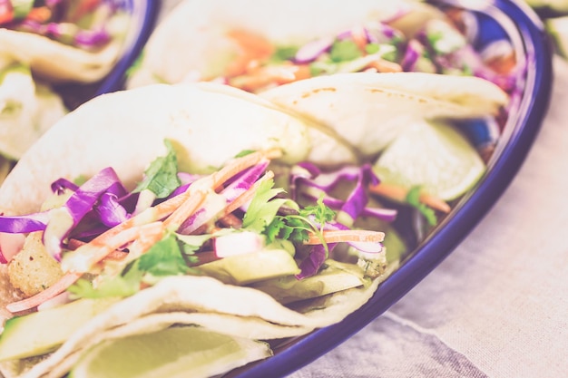 Fresh fish tacos with vegetables and guacamole salsa on a white corn tortillas.