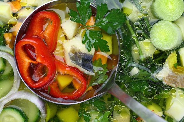 Fresh fish and vegetable soup with a ladle spoon in it background