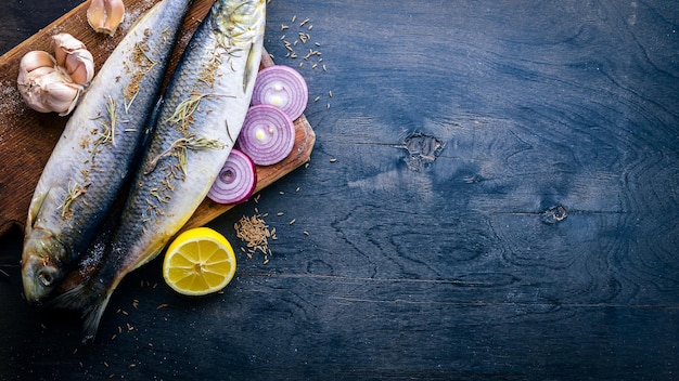 Fresh fish with vegetables spices and oil On a black wooden background Free space for text Top view