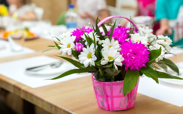 Fresh flower bouquet decorated with basket. Floral composition on wooden table