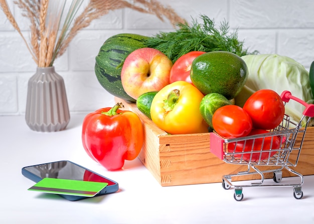 Fresh food and vegetables in green shopping cart on mobile smartphone, online grocery concept