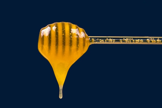 Fresh fragrant honey dripping from a spoon into a plate on a blue background organic vitamin nutrition