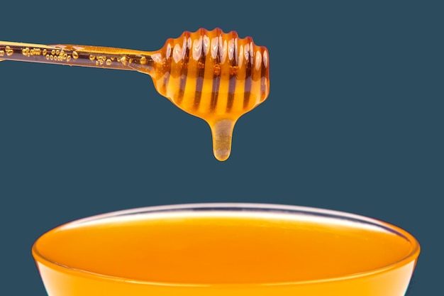 Fresh fragrant honey drips from a spoon into a plate on a colored background organic vitamin nutrition dessert food