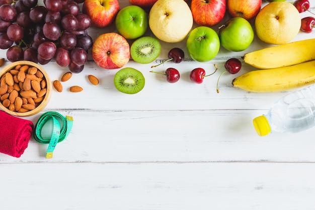 Fresh fruit with water on white wooden background