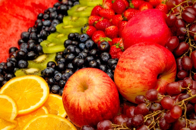 Fresh fruits concept Arrangement of kiwi orange apple and assorted burry as background