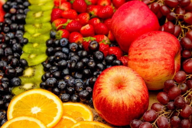 Fresh fruits concept Arrangement of kiwi orange apple and assorted burry as background