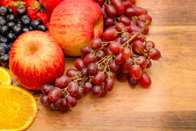 Fresh fruits concept Healthy fruits consist of grapes apple orange and berry on wooden background