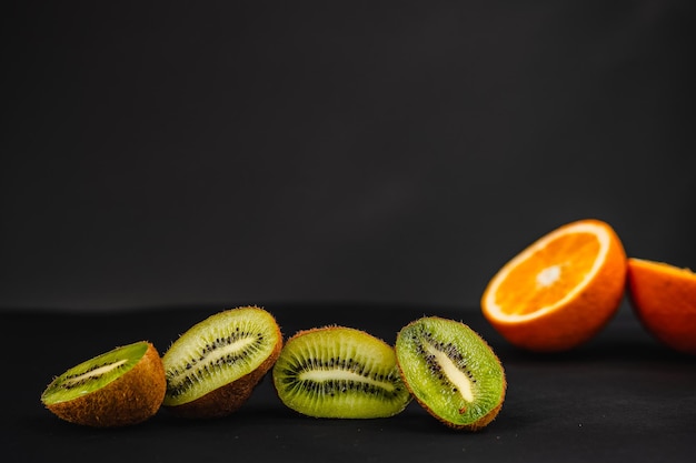 Fresh fruits on a dark background Orange and kiwi in a cut isolated on a black background Copy space high resolution product