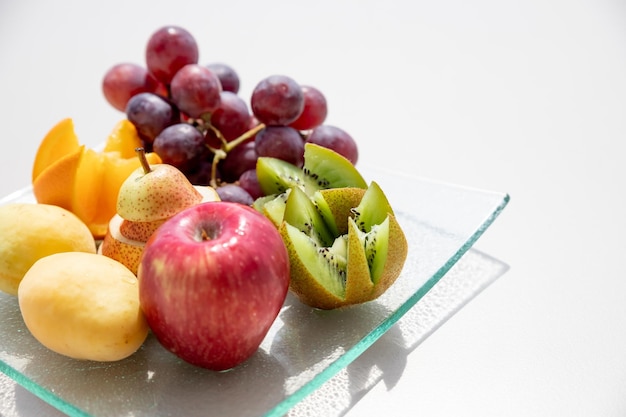 Fresh fruits in plate on white table Acceptable fruits for diabetes Kiwisgrapesorange applespearsHealthy diet and lowcalorie dietHealthy vegetarian food copy space