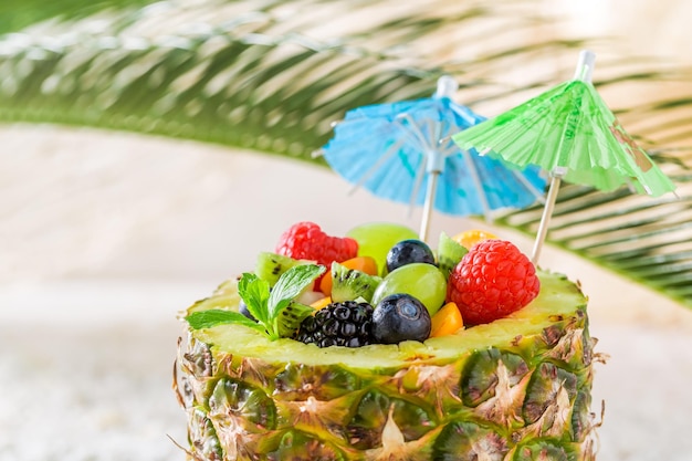 Fresh fruits salad in pineapple with cocktail umbrellas