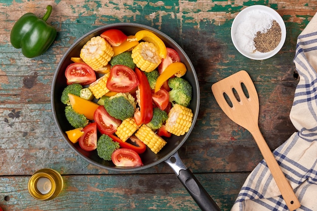 Fresh fruits and vegetables on a frying pan on an old wood background