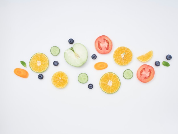 Fresh fruits and vegetables sliced on white background