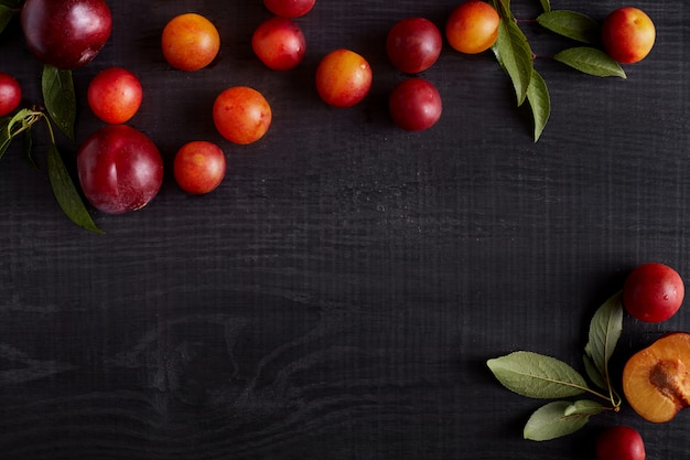 Fresh fruits with leaves on dark wooden rustic background,