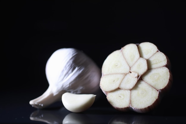 Fresh garlic clove on black background. Garlic is rich in vitamins, useful spring, good spices. Garlic sliced on a dark background. Raw sliced garlic.