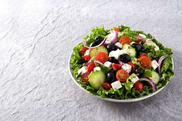 Fresh Greek salad in Plate with black olive,tomato,feta cheese, cucumber and onion on gray Copyspace