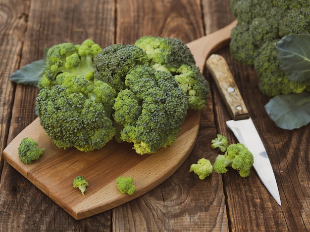 Fresh green broccoli on a wooden cutting board with a knife Broccoli cabbage leaves