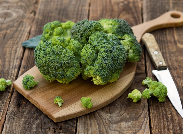 Fresh green broccoli on a wooden cutting board with a knife Broccoli cabbage leaves