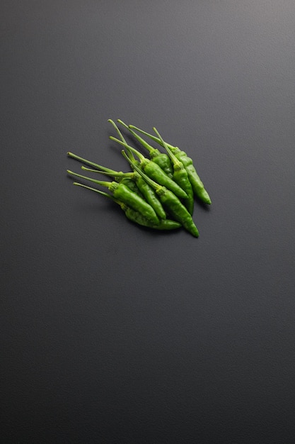 Fresh green chili isolated on black dramatic background