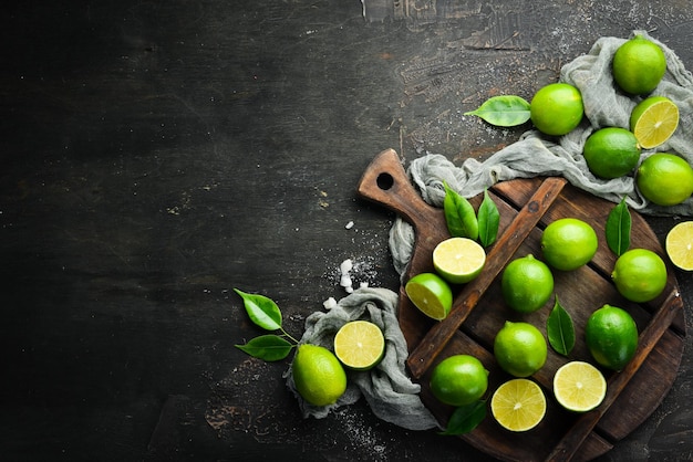 Fresh green limes with leaves Citrus fruits On a black stone background Top view Free space for your text