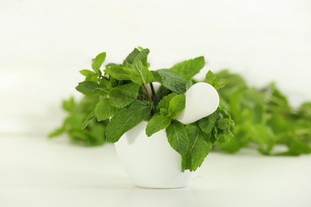 Fresh green mint in mortar on white background