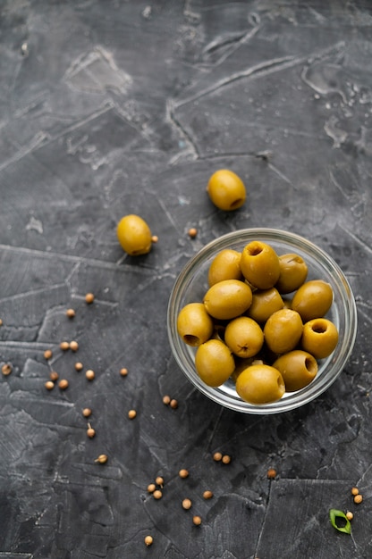 Fresh green olives in a glass plate on a dark background. view from above. Copy space