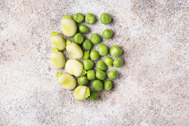 Fresh green peas and beans on light background