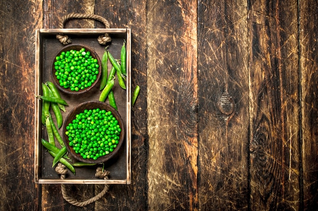 Fresh green peas in a bowl. On a wooden background.