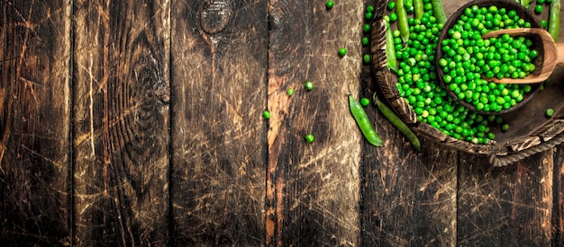 Fresh green peas in a bowl. On a wooden background.