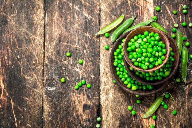 Fresh green peas in a bowl. On a wooden background.