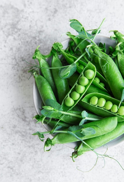 Fresh green peas pods and green peas with sprouts on concrete background. Concept of healthy eating, fresh vegetables.