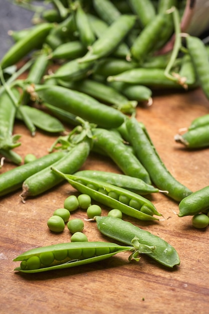 Fresh green peas pods on a wooden board.