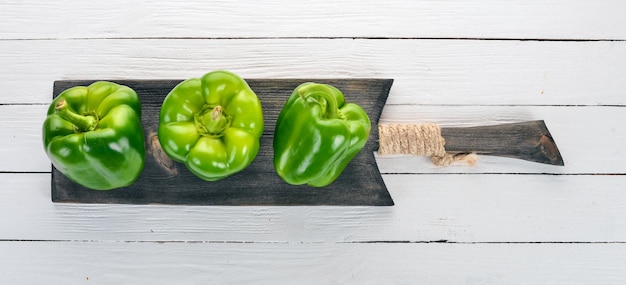 Photo fresh green pepper in a wooden box on a white wooden table top view free space for text